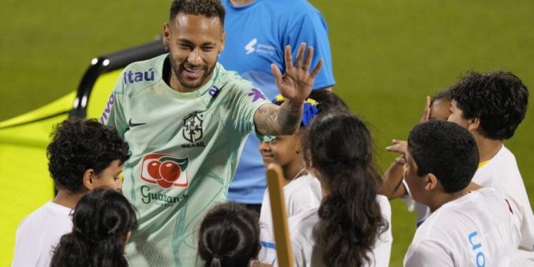 Neymar saluda a niños de un proyecto de la FIFA en un entrenamiento en el estadio Grand Hamad en Doha, Qatar, el 20 de noviembre de 2022. (AP Foto/Andre Penner)