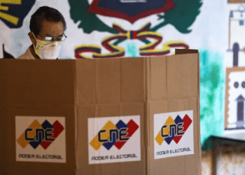 ARCHIVO - Un hombre parado frente a una cabina de votación en un colegio electoral durante las elecciones parlamentarias en Caracas, Venezuela, en diciembre de 2020.