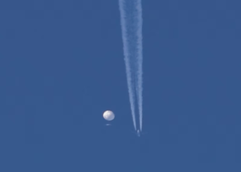 Un gran globo se desplaza sobre el área de Kingston, N.C., con un avión y su estela debajo de él. Estados Unidos dice que es un globo espía chino que se mueve hacia el este sobre EEUU a una altitud de 18.600 metros. (Brian Branch via AP)