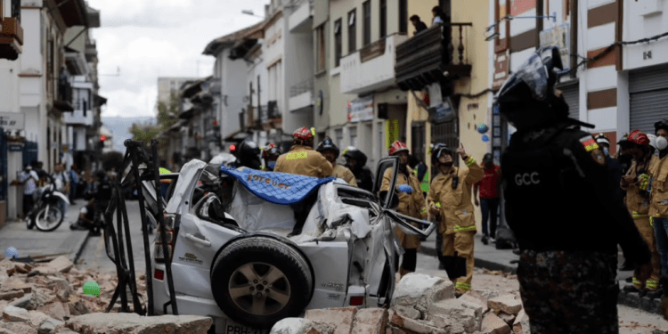 Un policía junto a un automóvil aplastado por los escombros después de que un terremoto sacudiera Cuenca, Ecuador, el sábado 18 de marzo de 2023. (AP Foto/Xavier Caivinagua)