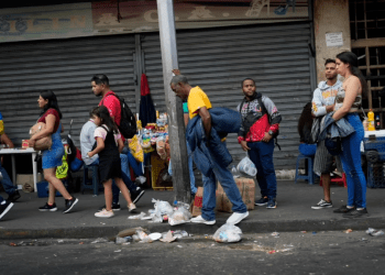 Varias personas hacen fila mientras esperan un transporte público en Caracas, Venezuela, el lunes 27 de febrero de 2023. (Foto AP/Ariana Cubillos)