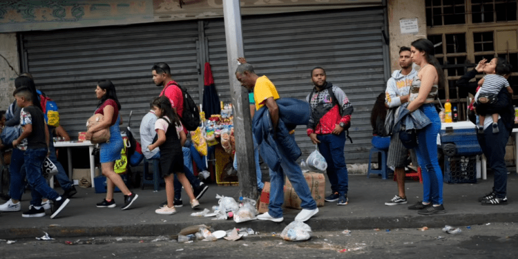 Varias personas hacen fila mientras esperan un transporte público en Caracas, Venezuela, el lunes 27 de febrero de 2023. (Foto AP/Ariana Cubillos)