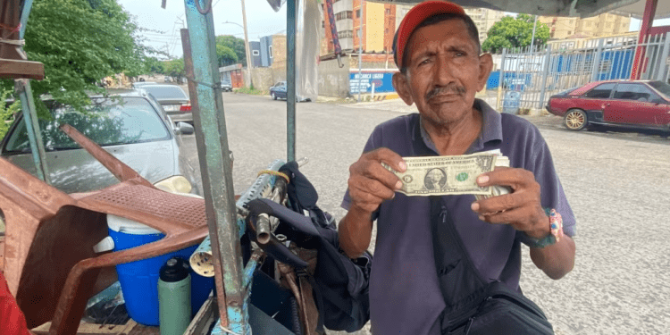 Un vendedor ambulante de golosinas y cigarros muestra un billete de un dólar estadounidense en Maracaibo, Venezuela.