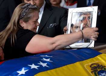 Liz Alban, hermana del ex concejal Fernando Alban, coloca un retrato de su pariente junto al de Jesucristo sobre su ataúd durante una ceremonia solemne en el Parlamento venezolano, el 9 de octubre de 2018, en Caracas.