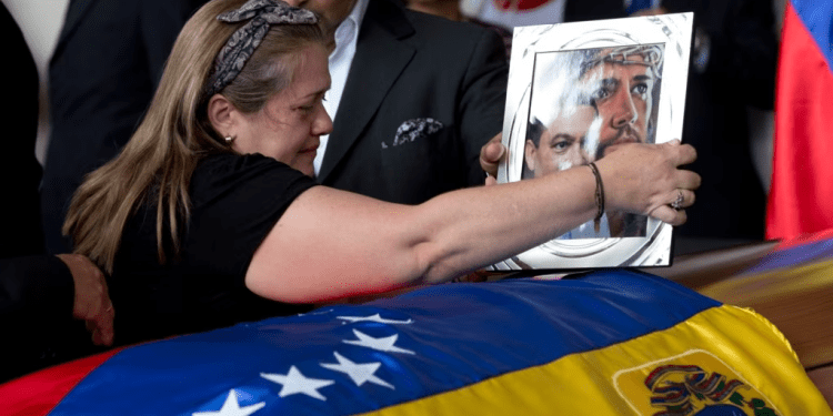 Liz Alban, hermana del ex concejal Fernando Alban, coloca un retrato de su pariente junto al de Jesucristo sobre su ataúd durante una ceremonia solemne en el Parlamento venezolano, el 9 de octubre de 2018, en Caracas.