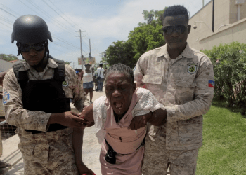 Oficiales de la Policía Nacional de Haití ayudan a una mujer afectada por gases lacrimógenos después de que la policía desalojara a personas que huían de la amenaza de bandas armadas, frente a la Embajada de Estados Unidos, en Puerto Príncipe, Haití, el 25 de julio de 2023.