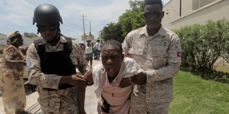 Oficiales de la Policía Nacional de Haití ayudan a una mujer afectada por gases lacrimógenos después de que la policía desalojara a personas que huían de la amenaza de bandas armadas, frente a la Embajada de Estados Unidos, en Puerto Príncipe, Haití, el 25 de julio de 2023.