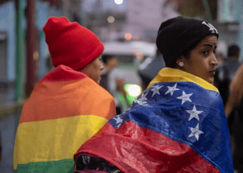 ARCHIVO - Una persona envuelta en una bandera venezolana camina con un grupo de migrantes que salen de la ciudad de Tapachula en el estado de Chiapas, México, a principios del 6 de junio de 2022.