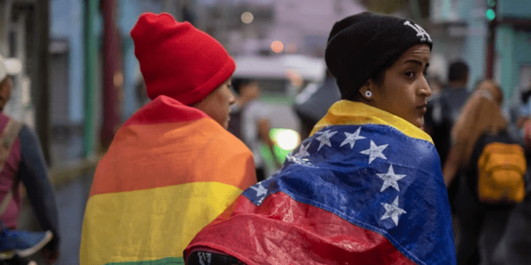 ARCHIVO - Una persona envuelta en una bandera venezolana camina con un grupo de migrantes que salen de la ciudad de Tapachula en el estado de Chiapas, México, a principios del 6 de junio de 2022.