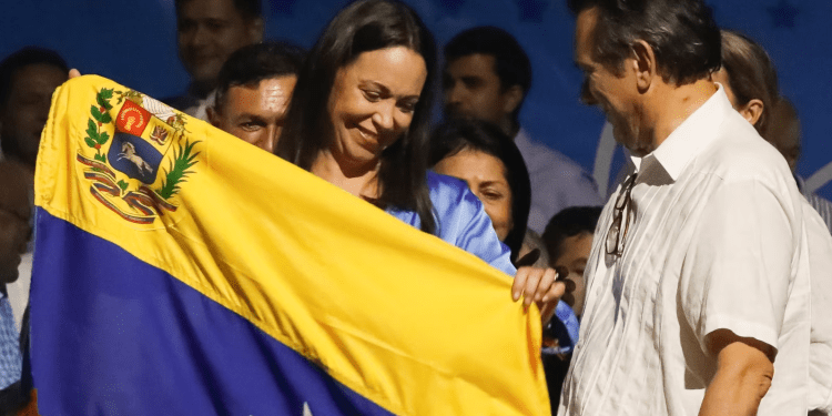 María Corina Machado, inminente ganadora de la primaria presidencial opositora, sostiene una bandera de Venezuela en su comando de campaña, amaneciendo este lunes 23 de octubre de 2023.