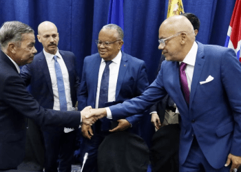 Los jefes de las delegaciones negociadoras de Venezuela, Gerardo Blyde (izquierda) y Jorge Rodríguez (derecha), se saludan frente a delegados internacionales en Barbados, durante la firma de acuerdos políticos, el martes 17 de octubre de 2023.