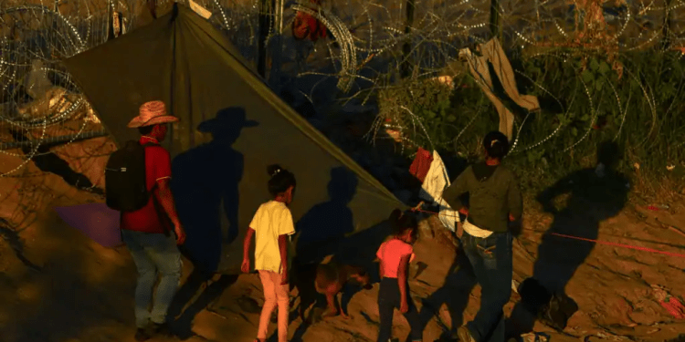 Migrantes que buscan asilo en Estados Unidos caminan cerca de una cerca con púas, en Ciudad Juarez, México. Estados Unidos y Venezuela acordaron un plan de repatriación con vuelos directos de quienes no tengan base legal para quedarse en el país norteamericano.