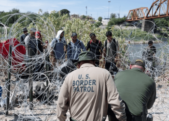Migrantes venezolanos esperan a que la policía fronteriza de Estados Unidos corte el alambre que les impide El Paso luego de haber cruzado el Río Grande hacia Eagle Pass, Texas, el pasado 24 de septiembre. Las autoridades arrestaron a un presunto miembro de El Tren de Aragua.