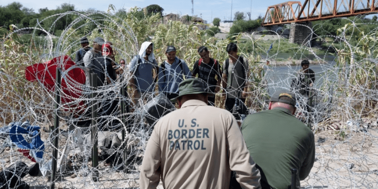 Migrantes venezolanos esperan a que la policía fronteriza de Estados Unidos corte el alambre que les impide El Paso luego de haber cruzado el Río Grande hacia Eagle Pass, Texas, el pasado 24 de septiembre. Las autoridades arrestaron a un presunto miembro de El Tren de Aragua.