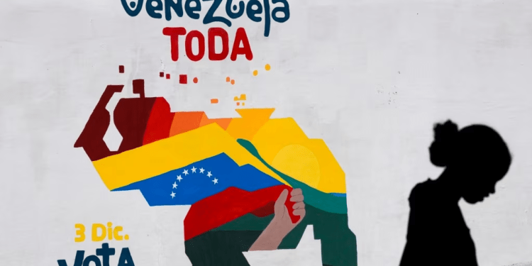 Una mujer vende frutas frente a un mural con el mapa de Venezuela donde se promueve la participación pro oficialista en el referendo consultivo del domingo, en Caracas, el 29 de noviembre de 2023.