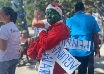 Trabajadores activos y jubilados de Venezuela, uno de ellos disfrazado del personaje el Grinch, se manifiestan por mejores salarios, el pago completo de aguinaldos y pensiones más "dignas" en Caracas, el 9 de noviembre de 2023.