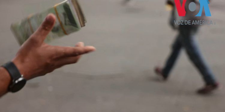 Personas dedicadas al cambio de dinero de manera informal en Venezuela venden pacas de bolívares, la devaluada moneda local, para operaciones de menudeo, completar un pago o para el pasaje del bus. Más del 90 % de los precios en el país están marcados en la moneda estadounidense, según expertos.