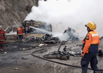 Bomberos y miembros de Protección Civil sofocan el fuego luego de un accidente que dejó al menos 14 muertos en la autopista Gran Mariscal de Ayacucho, en Miranda, este miércoles 13 de diciembre de 2023.
