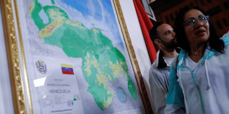 Dos personas conversan cerca de un mapa enmarcado de Venezuela, promovido por el gobierno de Nicolás Maduro para anexar un nuevo estado, el Guayana Esequiba, en Caracas, el 8 de diciembre de 2023.