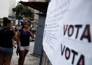 ARCHIVO - La gente mira dónde tienen que votar en una primaria para elegir un candidato de la oposición para enfrentar al presidente de Venezuela, Nicolás Maduro, en su probable candidatura a la reelección en 2024, en Caracas, el 22 de octubre de 2023.