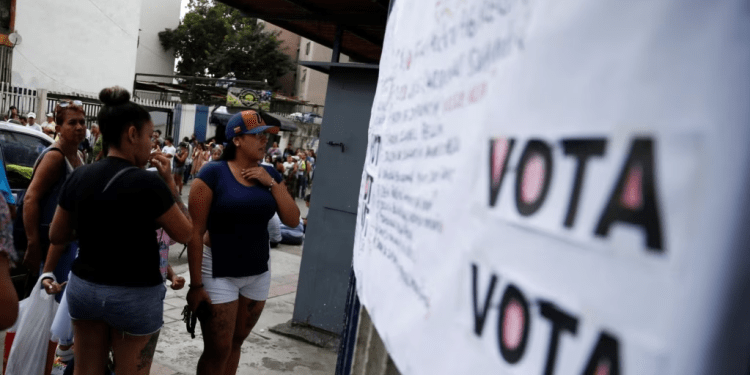ARCHIVO - La gente mira dónde tienen que votar en una primaria para elegir un candidato de la oposición para enfrentar al presidente de Venezuela, Nicolás Maduro, en su probable candidatura a la reelección en 2024, en Caracas, el 22 de octubre de 2023.