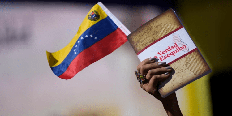 Una mujer sostiene una bandera venezolana y un libro sobre el Esequibo en Caracas, el pasado 29 de noviembre de 2023.