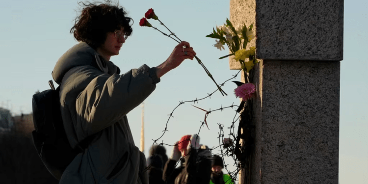 Una mujer deposita flores mientras la gente rinde homenaje a Alexei Navalny en el Memorial a las Víctimas de la Represión Política en San Petersburgo, Rusia, el 18 de febrero de 2024.