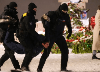 Agentes policiales detienen a un hombre que puso flores en un memorial del líder opositor ruso Alexei Navalny, en San Petesburgo, Rusia, el viernes 16 de febrero de 2024.