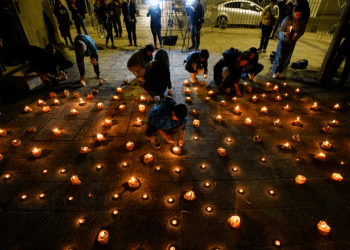 Varias personas encienden velas durante una vigilia frente a la sede de los Carabineros en honor de tres policías asesinados en el sur de Chile, el sábado 27 de abril de 2024, en Santiago.