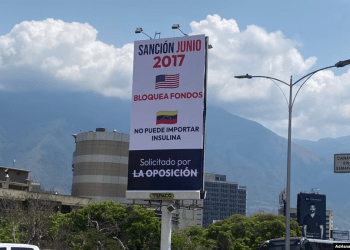 Mensajes que denuncian los efectos de las sanciones impuestas por EEUU contra Venezuela se ven en vallas en la principal autopista de la capital venezolana.