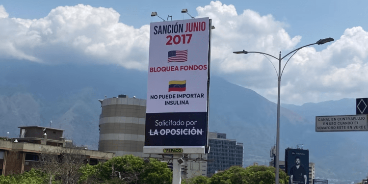 Mensajes que denuncian los efectos de las sanciones impuestas por EEUU contra Venezuela se ven en vallas en la principal autopista de la capital venezolana.