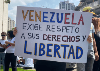 Una mujer muestra un cartel donde exige mejoras salariales al gobierno de Venezuela, durante una movilización por el Día del Trabajador en Caracas, el 1 de mayo de 2024.