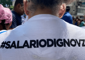 Una trabajadora muestra un eslogan por mejores condiciones laborales grabado en su camiseta, durante una protesta celebrada el 1 de mayo de 2024 en Caracas.