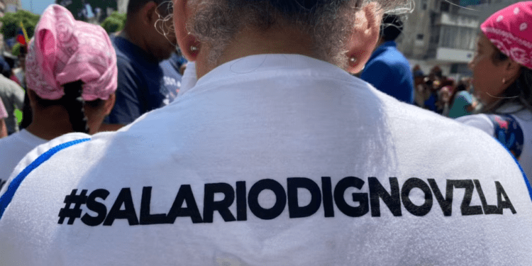 Una trabajadora muestra un eslogan por mejores condiciones laborales grabado en su camiseta, durante una protesta celebrada el 1 de mayo de 2024 en Caracas.