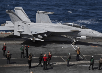 Un F-18 Super Hornet de la Marina de EEUU y miembros de la tripulación se ven en la cubierta de vuelo del USS Nimitz frente a la costa de Busan, Corea del Sur, el lunes 27 de marzo de 2023.