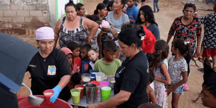 La gente recibe alimentos de Carolina Leal, directora y fundadora de la fundación Alimentando sueños, en Maracaibo, Venezuela, 12 de junio de 2024.