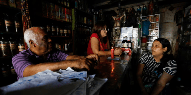 Trabajadores conversan cerca de una vela en un establecimiento durante un apagón en Caracas el 30 de agosto de 2024.