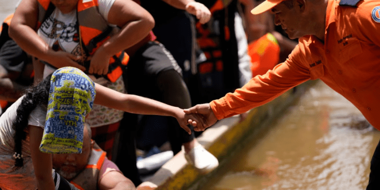 ARCHIVO - Un funcionario de protección civil ayuda a los migrantes a bajar de un barco en Lajas Blancas, Panamá, el 28 de junio de 2024, después de que los migrantes cruzaron caminando el Tapón del Darién desde Colombia.