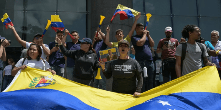 Una mujer sostiene una fotografía manipulada del candidato presidencial opositor Edmundo González Urrutia con una banda presidencial durante una protesta contra la reelección del presidente venezolano Nicolás Maduro, en Caracas, el 30 de julio de 2024.