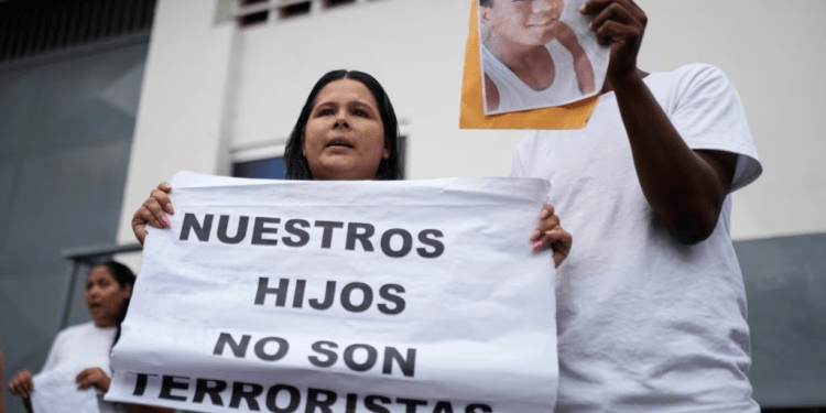 Dionexis García, hermana de Dioner Gómez, cuya fotografía muestra otro miembro de la familia, sostiene un cartel que dice en español "Nuestros hijos no son terroristas" afuera de un centro de detención, donde se encuentran algunos menores en Caracas.