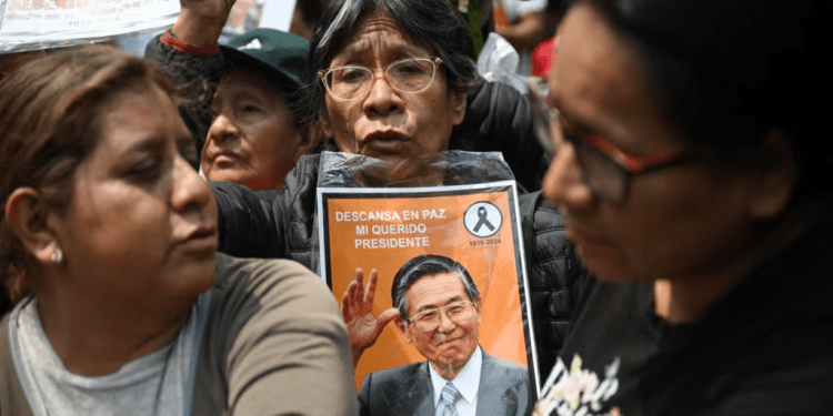 Una mujer sostiene un retrato del fallecido expresidente peruano Alberto Fujimori mientras espera la llegada del ataúd al cementerio Campo Fe de Huachipa durante su funeral de estado en Lima el 14 de septiembre de 2024.
