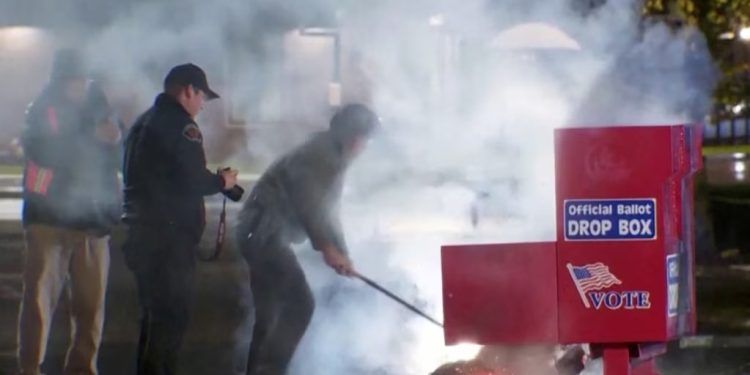 Rescatistas sacan el contenido en llamas de una urna electoral después de que estallara en llamas en un presunto incendio provocado en Vancouver, Washington, el 28 de octubre de 2024. (Evan Bell/ABC Affiliate KATU via Reuters)