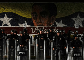 Funcionarios de la Policía Nacional Bolivariana se forman frente a un mural del Libertador Simón Bolívar en Caracas, el 31 de julio de 2024, después de dos días de protestas contra los resultados de la elección presidencial en Venezuela.