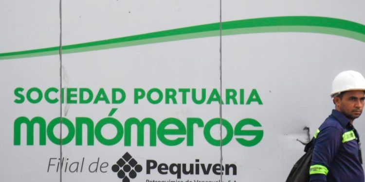 ARCHIVO - Un trabajador camina cerca de una valla con el logo de Monómeros en Barranquilla, Colombia, el 9 de octubre de 2021.