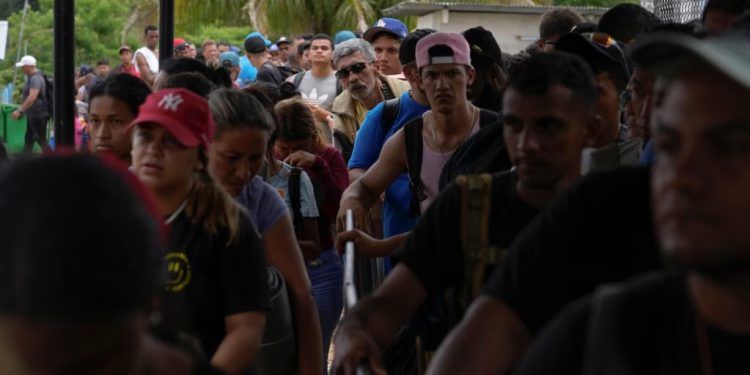 Migrantes que atravesaron el Tapón del Darién se alinean para inspecciones de sus pertenencias en Lajas Blancas, Panamá, el 26 de septiembre de 2024. Según el gobierno panameño, más de 196.000 venezolanos han cruzado esa zona boscosa de forma ilegal. (ARCHIVO: AP)