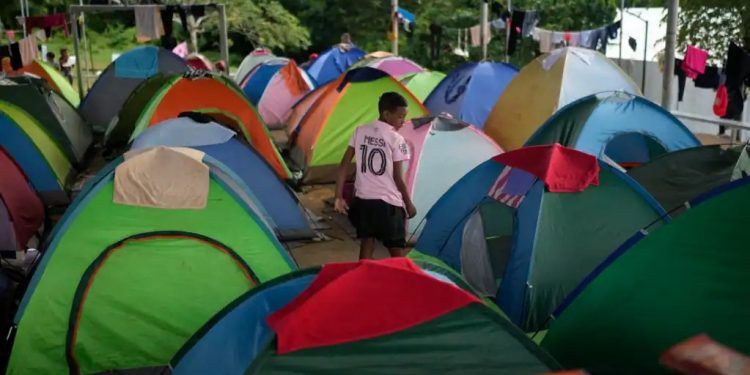 ARCHIVO - Un migrante que cruzó a pie el Tapón del Darién desde Colombia, camina entre tiendas de campaña en un campamento temporal en Lajas Blancas, Panamá, el 28 de junio de 2024.