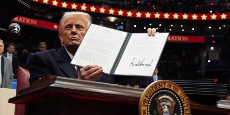 El presidente Donald Trump firma una orden ejecutiva mientras asiste a un desfile inaugural presidencial en el Capital One Arena, el 20 de enero de 2025, en Washington.